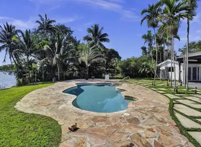a swimming pool in a yard with a stone patio at Casa Ocaso in Miami