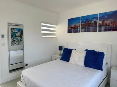 a bedroom with a white bed with blue pillows at Villa Clara Blue-Little Havana in Miami