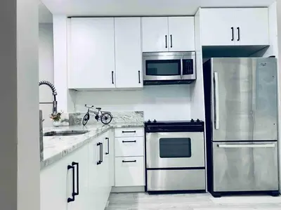 a kitchen with white cabinets and a stainless steel refrigerator at Modern 1BR 1BA Condo 1Block to Aventura Mall in Aventura