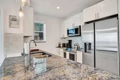 a kitchen with white cabinets and a granite counter top at Sunset Oceanfront Paradise in Hollywood