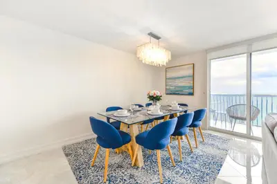 a dining room with a table and blue chairs at Open the Window and Enjoy the Sea Breeze at Exclusive Condo! in Miami