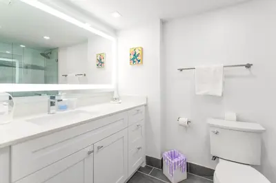 a white bathroom with a toilet and a large mirror at Open the Window and Enjoy the Sea Breeze at Exclusive Condo! in Miami