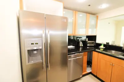 a stainless steel refrigerator in a kitchen with wooden cabinets at Castle L5 Oceanview Double-loft with pool, beach access, tennis, free parking! in Miami Beach