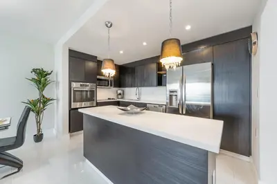 a kitchen with a white counter top and black cabinets at Sunny Isles Beachfront Oasis, Modern & Spacious in Sunny Isles Beach