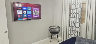 a chair in a room with a television on a wall at Big TV 2 Bedroom Apartment Cooper City in Cooper City