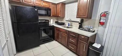 a kitchen with a black refrigerator and a sink at Big TV 2 Bedroom Apartment Cooper City in Cooper City
