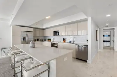 a kitchen with white cabinets and a white counter top at Escape to Beachwalk Resort in Chic Apartment in Hallandale Beach