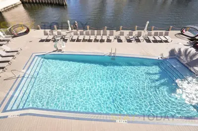 a large swimming pool with chairs and water at Escape to Beachwalk Resort in Chic Apartment in Hallandale Beach