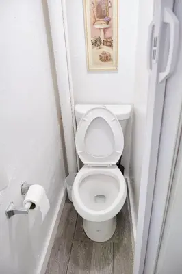 a white toilet in a bathroom with a roll of toilet paper at The Tiny Red Mini Studio At Little Havana in Miami