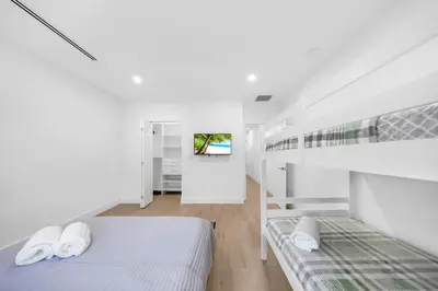 a white room with two beds and a tv at Up to 12 guests! Modern Villa near Wynwood 29! in Miami