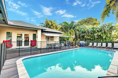 a swimming pool with chairs and a house at Ultimate Retreat 6BR & 3BA Villa near Beach in Dania Beach