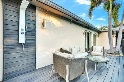 a patio with wicker chairs and a table on a deck at Ultimate Retreat 6BR & 3BA Villa near Beach in Dania Beach