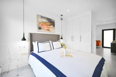 a white bedroom with a large bed with a blue stripe at Stylish Oasis in Design District, Near Wynwood in Miami