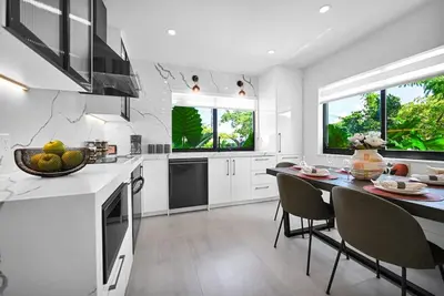 a white kitchen with a table and chairs in it at Stylish Oasis in Design District, Near Wynwood in Miami