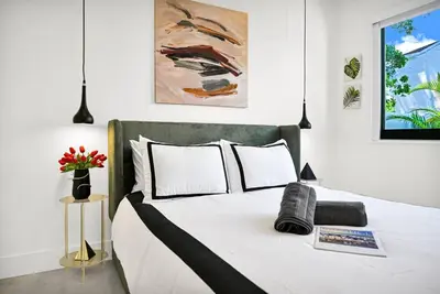 a bedroom with a large bed with white sheets at Stylish Oasis in Design District, Near Wynwood in Miami