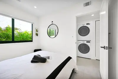 a white bedroom with a bed and two washing machines at Stylish Modern Home near Wynwood & Design District in Miami