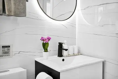 a white bathroom with a sink and a mirror at Stylish Modern Home near Wynwood & Design District in Miami