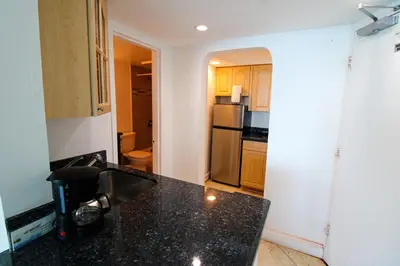 a kitchen with a black counter top and a refrigerator at Castle 830 OceanView Balcony Studio, Pool, Tennis, Free Parking in Miami Beach