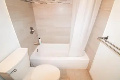 a white bathroom with a toilet and a tub at Castle 830 OceanView Balcony Studio, Pool, Tennis, Free Parking in Miami Beach
