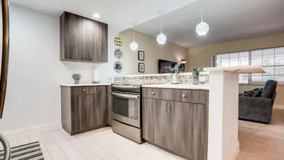 a kitchen with wooden cabinets and a living room at Serene 1BR Haven Fort Lauderdale in Fort Lauderdale