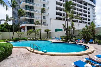 a swimming pool with chairs and a building at Welcome to our beach home! in Hollywood