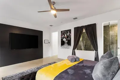 a bedroom with a large bed and a flat screen tv at Luxury Mansion, Game Room, Pool, Rooftop, Skyline, Walk to Las Olas in Fort Lauderdale