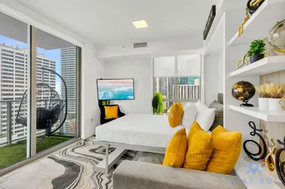 a white bedroom with a bed and a large window at Beautiful Apartment with gym and amazing Pool in Miami
