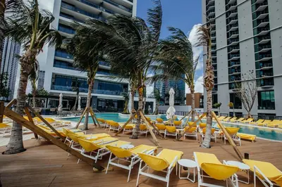 a pool with yellow lounge chairs and palm trees at New unit 28th Floor with Unbeatable Bayside Views in Miami