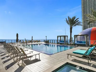 a swimming pool with lounge chairs and the ocean at Seaside Elegance 1BR Retreat Stunning View in Hollywood