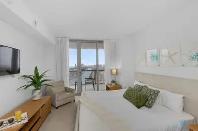 a white living room with a bed and a television at Amazing Pool Infinity View and Gym in Hallandale Beach