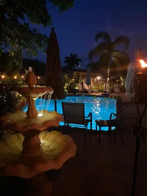 a pool at night with a table and chairs and a fountain at Wilton Manors A Mens Oasis in Fort Lauderdale