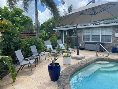 a pool with chairs and an umbrella next to a house at Wilton Manors A Mens Oasis in Fort Lauderdale
