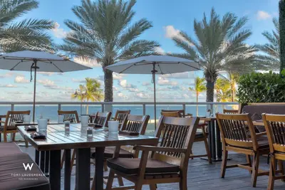 a restaurant with tables and chairs and palm trees at Stylish 1BR Suite with 5 Star Amenities and Stunning Views in Fort Lauderdale