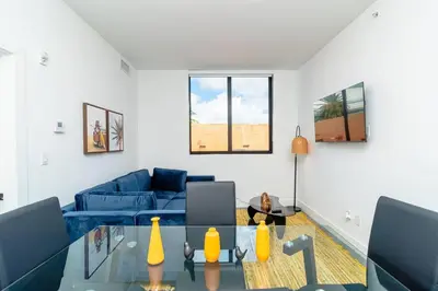 a living room with a blue couch and a glass table at Cozy Miami 2BR Oasis Near Brickell, Calle Ocho & Marlins Stadium in Miami