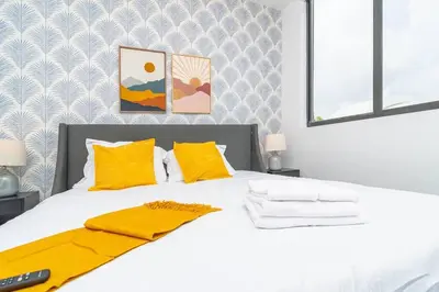 a bedroom with a white bed with yellow pillows at Modern Cozy 2BR Oasis with King Beds Near Marlins Park & Brickell in Miami