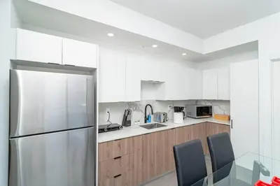 a kitchen with white cabinets and a stainless steel refrigerator at Modern Cozy 2BR Oasis with King Beds Near Marlins Park & Brickell in Miami