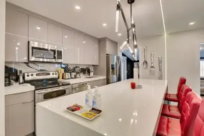 a kitchen with a white counter and red chairs at Flamingo House with Cinema, Pool & Chill Area in Miami
