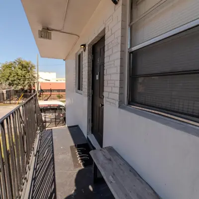 a wooden bench sitting outside of a building with a window at Queens Cozy Condo Near Downtown Airport in Miami