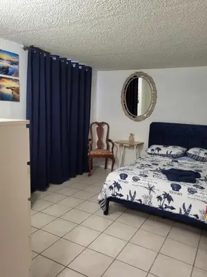 a bedroom with a bed with blue curtains and a chair at Azucar Miami in Miami