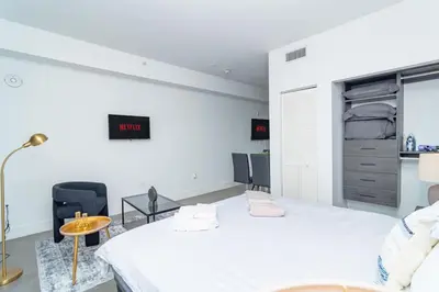 a white bedroom with a large bed and a chair at Chic Spacious Studio Miami Stay Near Marlins Park & Brickell in Miami