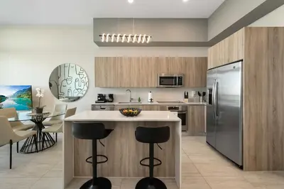 a kitchen with stainless steel appliances and a counter with stools at Luxury & Modern Condo in Design District with Pool in Miami