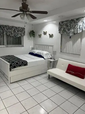 a bedroom with two beds and a couch and a ceiling fan at Private Studio in West Hialeah in Hialeah