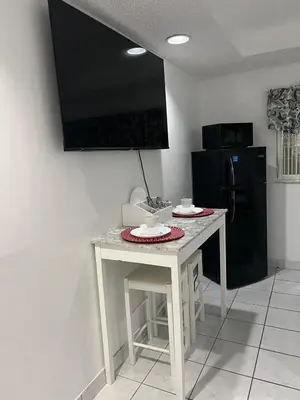 a white table in a kitchen with a black refrigerator at Private Studio in West Hialeah in Hialeah