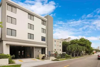 a white building on a street with a car parked in front at Central 1BR in Miami with King Bed Near Wynwood and Marlins Park in Miami