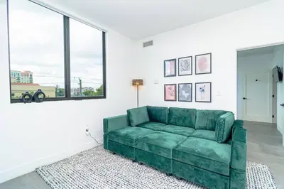 a green couch in a living room with windows at Miami 2BR Getaway with King Beds Near Marlins Park & Calle Ocho in Miami