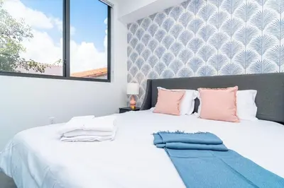 a bedroom with a white bed with pink and blue pillows at Modern 1BR Suite with King Bed Near Brickell, Downtown & Wynwood in Miami