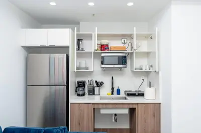 a small kitchen with white cabinets and a refrigerator at Modern 1BR Suite with King Bed Near Brickell, Downtown & Wynwood in Miami