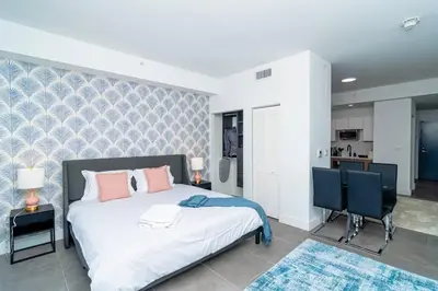 a bedroom with a bed and two chairs and a kitchen at Modern 1BR Suite with King Bed Near Brickell, Downtown & Wynwood in Miami