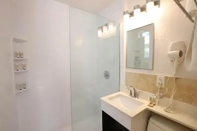 a white bathroom with a sink and a shower at Ocean Drive Suite in South Beach Family & Pet Friendly in Miami Beach