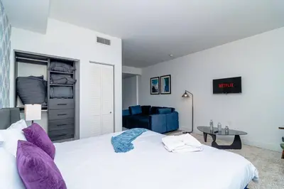 a bedroom with a white bed and a blue couch at Stylish Studio Miami Suite Oasis Near Calle Ocho & Brickell in Miami